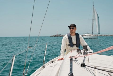 A yachtsman controls a sailing yacht on the open sea, demonstrating skills in maritime navigation